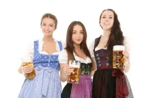 three women wearing Oktoberfest outfits holding beers