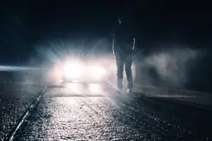 person standing in front of a car in the street at night