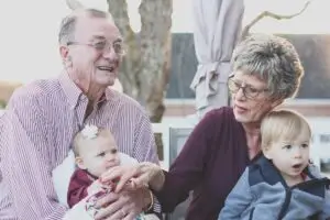two grandparents sitting and holding two babies