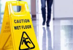 person walking near yellow wet floor sign