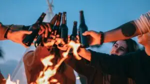 beer drinkers toasting bottles at a bonfire