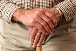 An elderly man holding a cane.