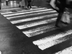 black & white photo of people walking through a crosswalk