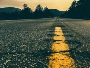 long highway with a forest and sunset background