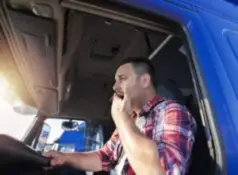 semi-truck driver yawning behind the wheel