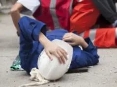 Construction worker in a hard hat on the ground after an accident.