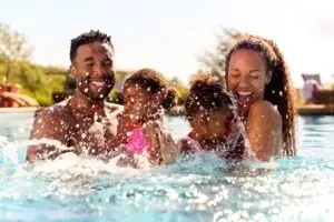 family laughing while splashing in pool