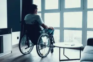 Man in wheelchair looks out window after experiencing disability discrimination at work