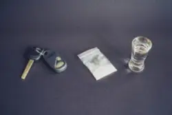 keys on a table next to drugs and liquor. Contact a DWAI drugs lawyer in Albany for help with your defense