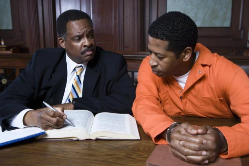 A criminal defense lawyer answering questions from a man sitting next to them who has been arrested.