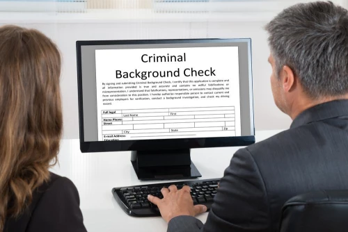 Two people complete a criminal background check on a computer. A domestic violence (DV) charge will show on a background check in California, whether it led to a conviction or not.