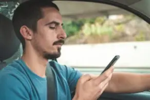 young man using a cell phone while driving