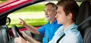 adult teaching teenager to drive car