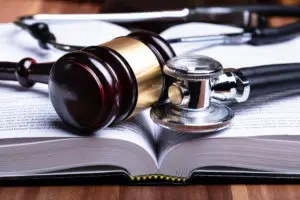 A gavel and stethoscope lay on top of a law book.