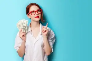 happy young woman holding wad of cash