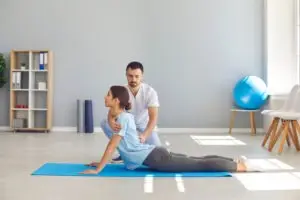 physical therapist helping woman do yoga for her back
