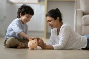 woman and son putting money in piggy bank