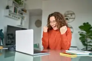 young woman excited to see slip-and-fall settlement money on computer