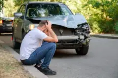 A man by his car after a head-on collision. In this situation, you can contact a head-on collision lawyer.
