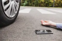 close-up of a man’s arm and cell phone lying on the road after a pedestrian accident