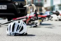 A damaged bicycle and cyclist helmet are lying on the ground after a collision with a car. A bicycle accident lawyer will help injured victims file for damages.