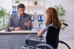 Woman in wheelchair sits across desk from attorney and asks how a workers' compensation settlement works