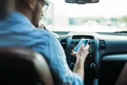 A driver staring at his phone while on the road. Distracted driving is one of the main causes of pedestrian accidents.