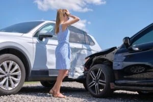 A woman stands by her damaged vehicle after a crash and wonders what the average settlement for a drunk driving accident is.