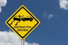 A sign on the road in Ohio that says distracted driving with a car colliding with another due to not paying attention