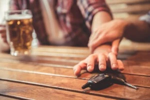 A hand being restrained by another person's hand to not reach for their keys to avoid drunk driving