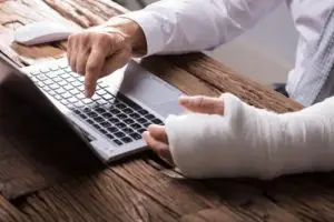 An injured worker tries to apply for benefits on their computer.
