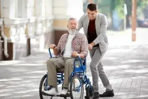 A young man pushes his father in a wheelchair.