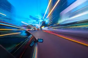 A car drives so fast, the lights outside the vehicle begin to blur.