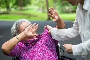 A nurse threatens to hurt an elderly woman in a wheelchair.