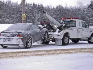 tow truck towing a car in the snow