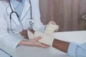 A doctor wraps a bandage around her patient’s hand.