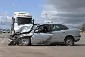 Severe damages on a car after a crash with a semi-truck on the road.