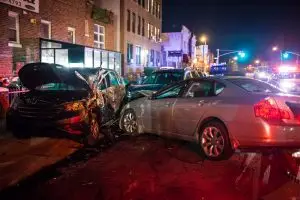 A car crashes into the side of another on the street at night.