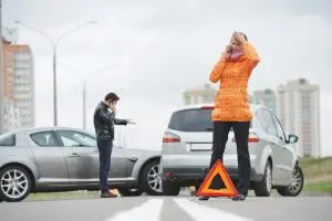 two frustrated people on their phones after car accident