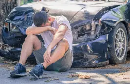 distraught motorist sits outside crashed car