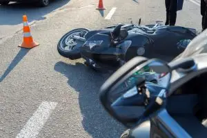 downed motorcycle in front of car and traffic cones