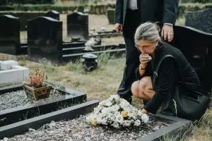 grieving woman lays flowers on grave