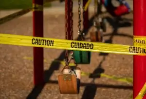 Caution tape around a swing set on a playground.