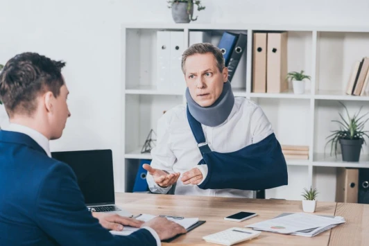 An injured man talks to a lawyer at his desk.