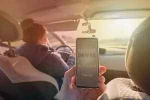 passenger in back seat using rideshare app