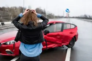 woman stands near broken cars