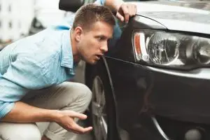 man inspecting accident damage