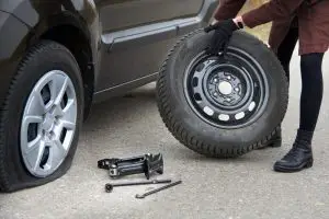 woman changing tire after accident