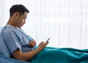injured man uses phone in hospital