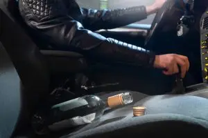 man driving with liquor bottle on front seat